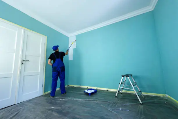 Professional painter painting a wall in blue
